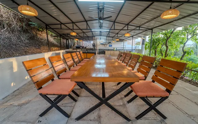 Covered dining deck with a long wooden table at Redroof